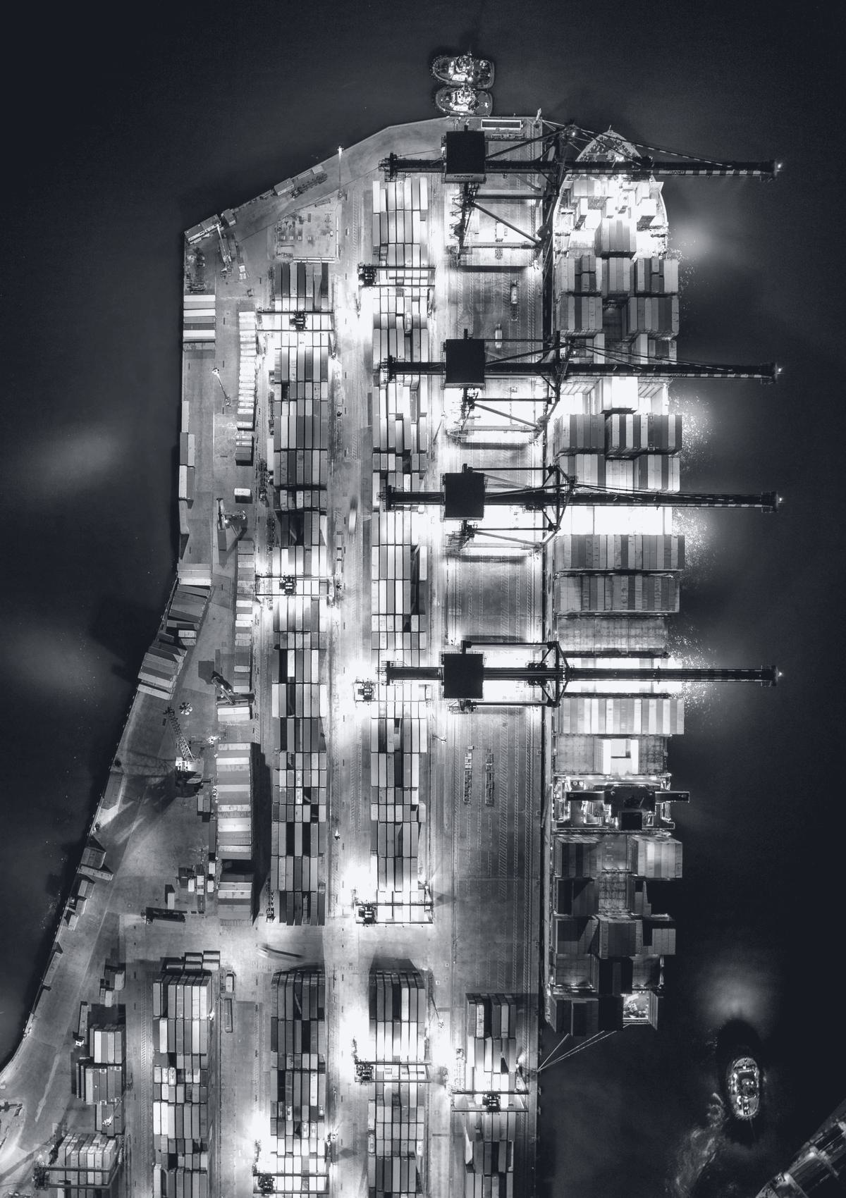 Overhead view of a container terminal lit at night.